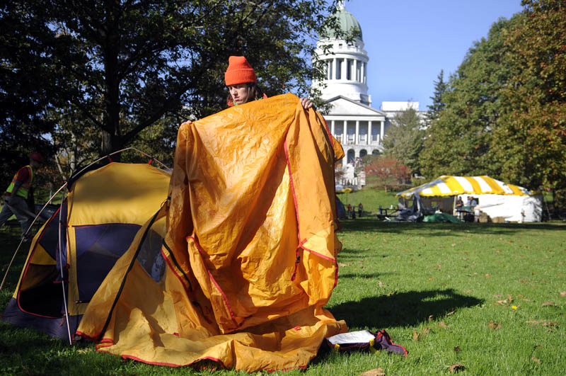 Daphne Loring shakes dew off a tarp Monday morning while breaking down her tent in Capitol Park. The Greene farmer spent two nights in the park as part of the Occupy Augusta protest. Loring said she needed to tend to the hogs she is raising but plans to return to the camp out.