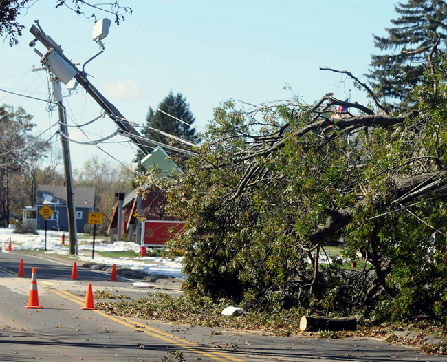 A snapped utility pole leans over the road today in Enfield, Conn., six days into an epic power outage that still has roughly 300,000 Connecticut residents in the dark.