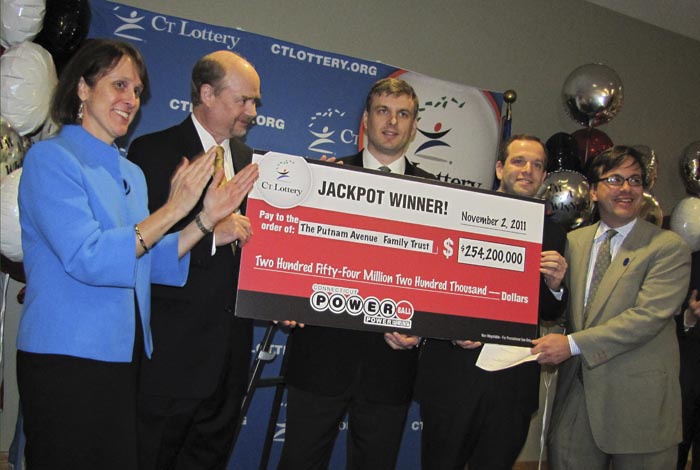 In this photo provided by the Connecticut Lottery in Greenwich, Conn., wealth managers Tim Davidson, second left, Greg Skidmore, center, and Brandon Lacoff, second right, pose Monday with a ceremonial check for $254.2 million. The jackpot was the largest ever won in Connecticut and the 12th biggest in Powerball history.