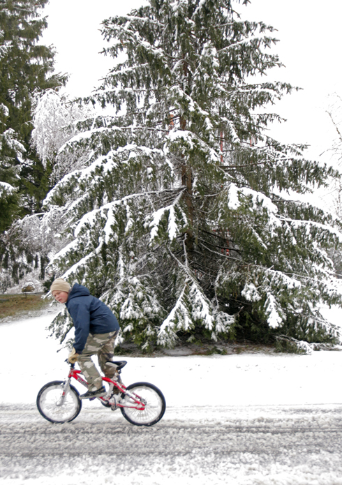 Emil Harmon rides his bicycle along snow-covered Route 117 in Hollis today.