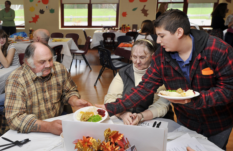 Gordon Chibroski / Staff Photographer. Wednesday, November 16, 2011. Kenneth Hutchins, left, and Karla Taylor of Cape Porpoise are served their meal by Alex Durrell, their grandson, at the Thanksgiving Dinner served by 8th graders to invited senior citizens at Middle School of the Kennebunks.