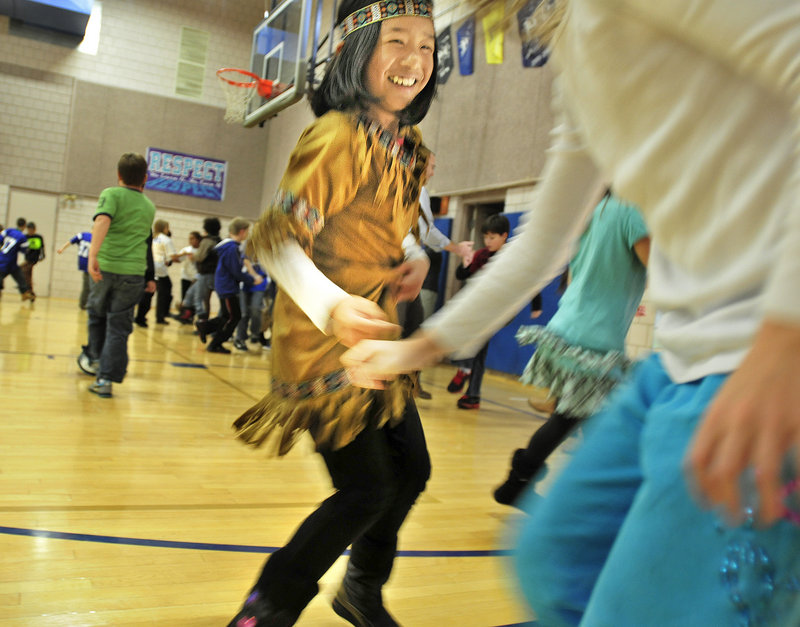 Abby Cotton, left, a Sea Road School fifth-grader, performs the mosquito dance with classmate Grace Thompson, right, to show their parents what they’d learned from the school’s artist in residence.