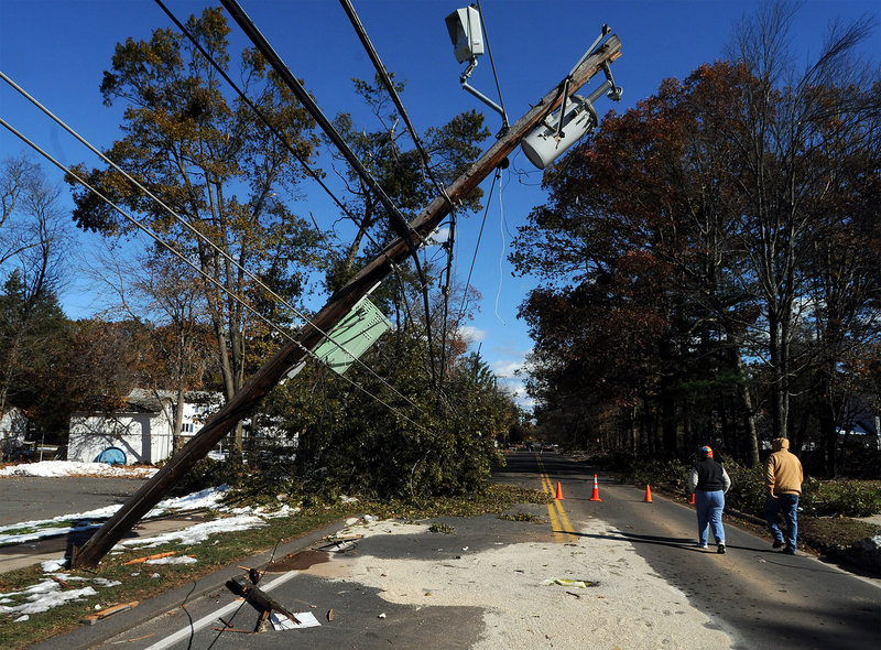 Joyce and Bob Mercik walk around a snapped utility pole on a closed road Friday in Enfield, Conn. Repair crews with Connecticut Light & Power have felt the wrath of customers as the utility struggles with what it calls “historic” outages.
