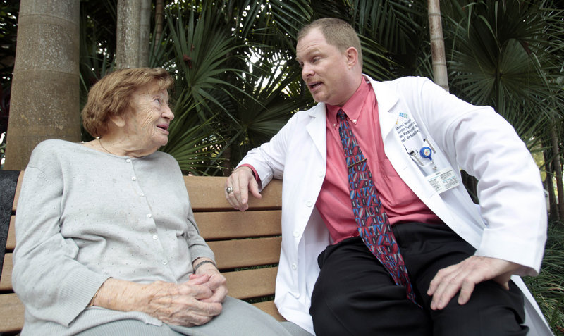 Dr. Brian Kiedrowski, right, talks to one of his patients, Victoria Cohen, 100, in Miami.
