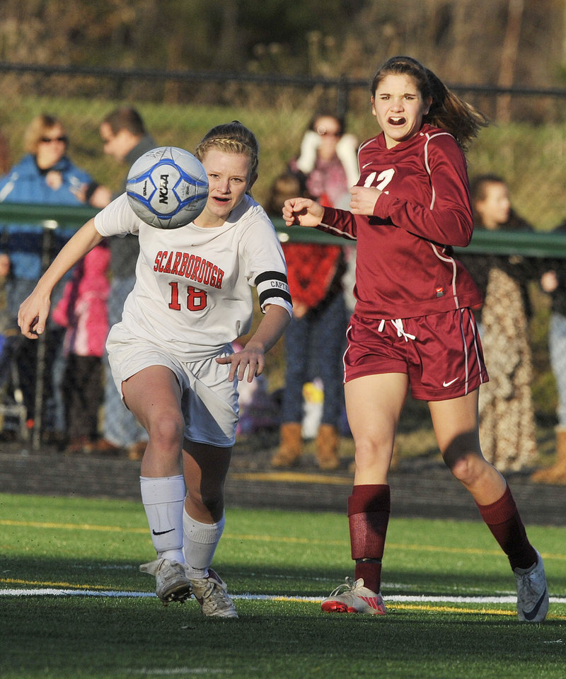 Haley Carignan, left, of Scarborough sends a shot toward the goal Saturday after slipping past Allison Vanidestine of Bangor in the Class A state final. Bangor won, 4-0.