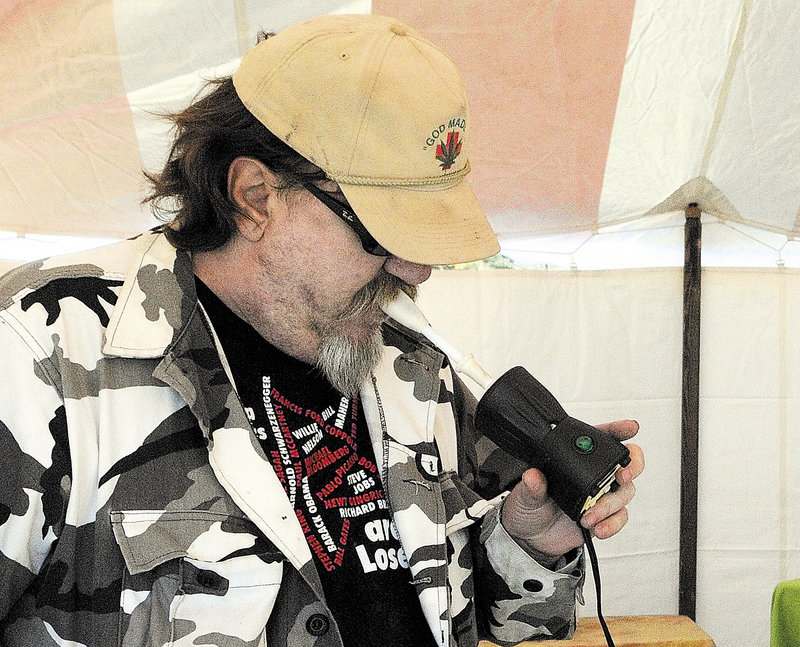 Chris Kenoyer uses a vaporizer to inhale marijuana during the Home Grown Maine trade show Saturday at the Augusta Civic Center. “This is the first time we’ve had permission to medicate in public,” he said. in the parking lot during the trade show, which continues today.