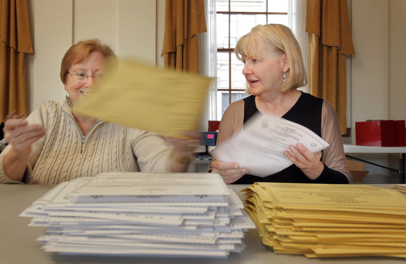 Elizabeth Boynton, left, and Teresa Bunn separate state and municipal absentee ballots Monday in the State of Maine Room at Portland City Hall. Boynton is a volunteer and Bunn is a vital records clerk for the city of Portland. Similar scenes played out around the state Monday.