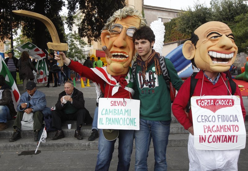 Among the thousands of Democratic party demonstrators seeking the ouster of Premier Silvio Berlusconi were these two in Rome on Saturday. They are wearing masks and signs mocking Berlusconi, right, and Reform Minister Umberto Bossi. The placards say “Silvio, change my diaper,” left, and “I’m looking for confidence, payment in cash.”