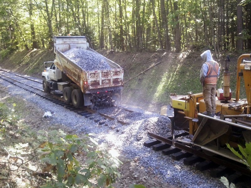 A dump truck distributes ballast prior to grading by machine. The upgrade project is expected to be done by spring.