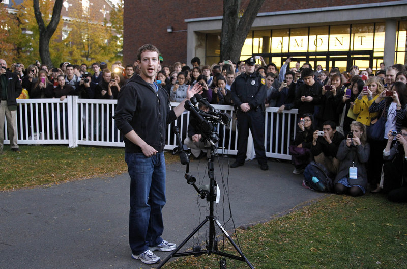 Facebook creator Mark Zuckerberg takes questions from members of the media as a crowd watches from behind temporary barriers on the campus of Harvard University in Cambridge, Mass., on Monday.