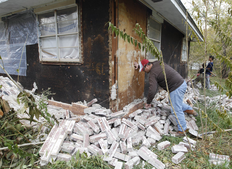 A man works Sunday to clear away bricks that fell from his in-laws’ home in Sparks, Okla., during Saturday’s earthquake. Experts say the quakes were natural, not the result of drilling.