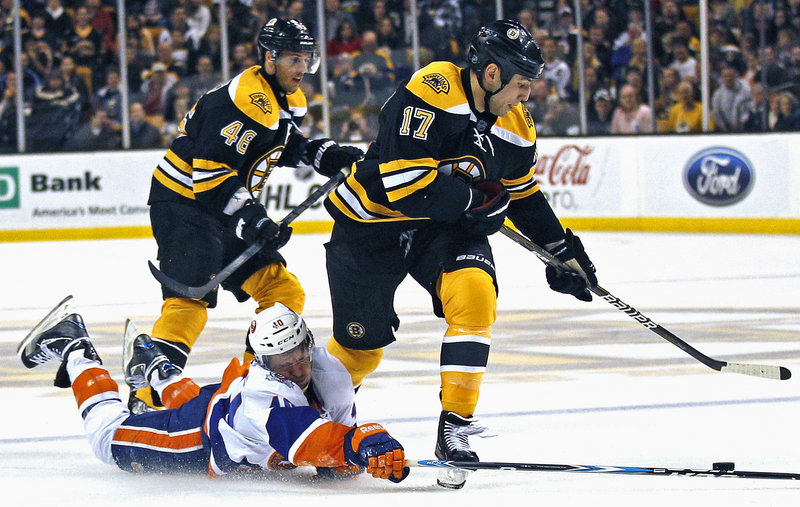 Michael Grabner of the Islanders tries to knock the puck free from Boston’s Milan Lucic in Monday night’s game in Boston. The Bruins won their third straight, 6-2.