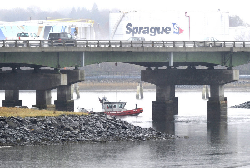 A Coast Guard vessel stands by under an I-295 overpass as a cleanup crew works along the Fore River at the end of a runway at the Portland International Jetport on Thursday.