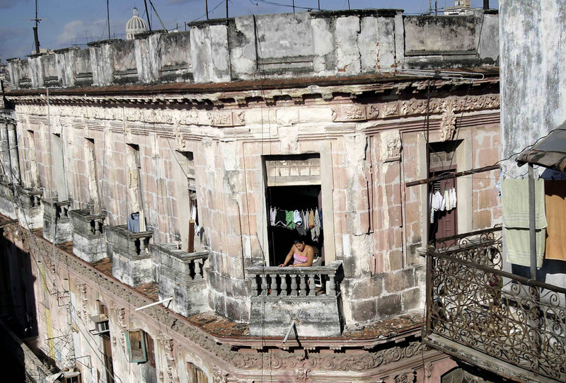 A woman looks out from an old building in Havana Friday. Cubans will now be able to buy and sell homes, President Raul Castro has delivered on his major promise this year to relax the government’s grip on the economy.
