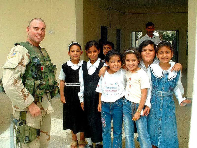 Army Capt. Christopher Cash, a soldier with roots in Maine, poses with Iraqi schoolchildren on the day before he was killed in a firefight with insurgents in Baqubah, Iraq, in 2006.