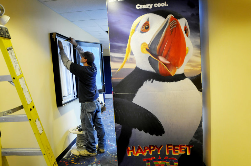 Kevin Ruel of Seabee Electric works on what will be a poster board display at the new Nordica Theatre. To the right is a display for the movie Happy Feet Two, which will show in 3-D during the theater s first week in business.