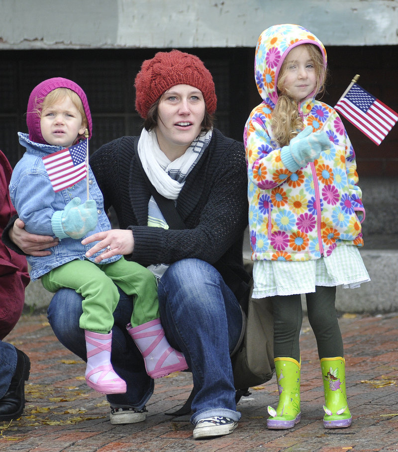 Clara, 2, left, and Willa Stefanski, 3, of Falmouth watch Portland’s Veterans Day parade along with their nanny, Melissa Anderson.