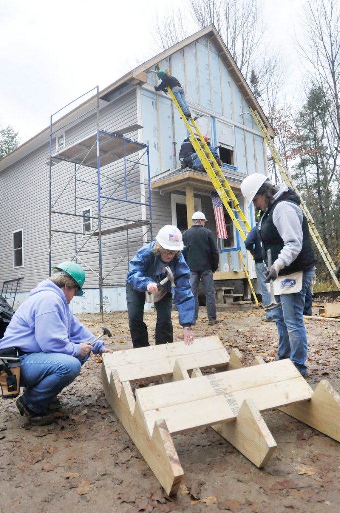 From left, Pat Iles of Brunswick, who served in the Navy, LaRhonda Harris of Jefferson, who served in the Air Force, and Jasmine Savoi, who works at the Veterans Center in Lewiston, work together to help Habitat for Humanity build homes in Freeport on Friday.