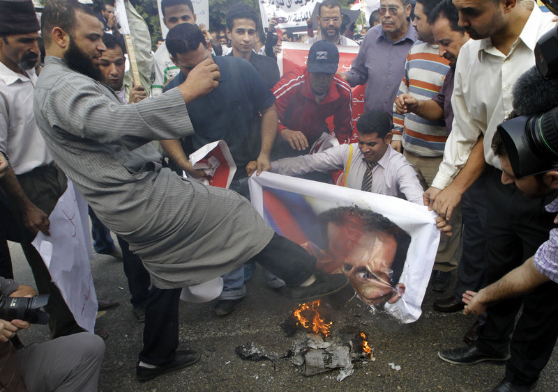 A Syrian protester kicks a burning picture of Syrian President Bashar Assad during a protest in front of the Arab League headquarters in Cairo on Saturday.