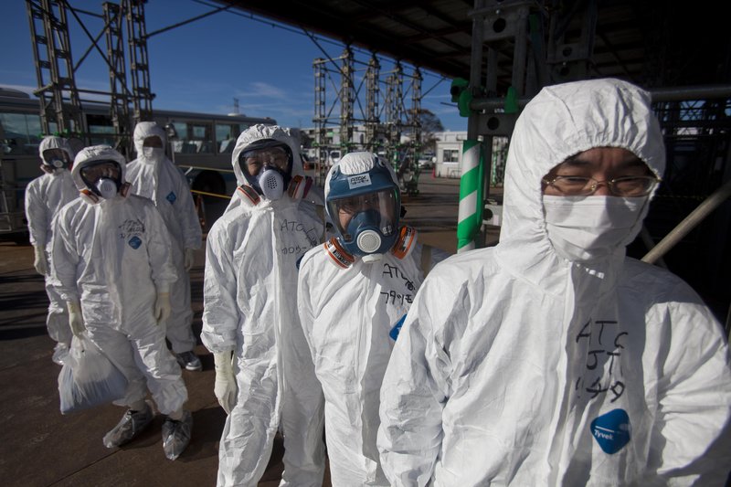 Workers in protective suits and masks wait to enter the emergency operation center at the crippled Fukushima Dai-ichi nuclear power station on Saturday. Reporters who were allowed to tour the plant found that much progress has been made but that years of work lie ahead.