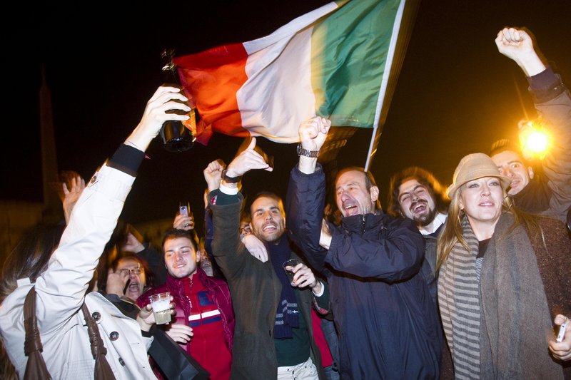 An Italian flag unfurled above them, people celebrate the resignation of Premier Silvio Berlusconi in Rome on Saturday. The beleaguered prime minister ended a 17-year political era and set in motion a transition aimed at bringing Italy back from the brink of economic crisis.