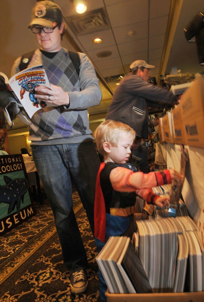 Josh Lovejoy, left, of South Portland looks over trade paperbacks as his son, Eamon, 2, dressed as Thor, plays with an action figure.