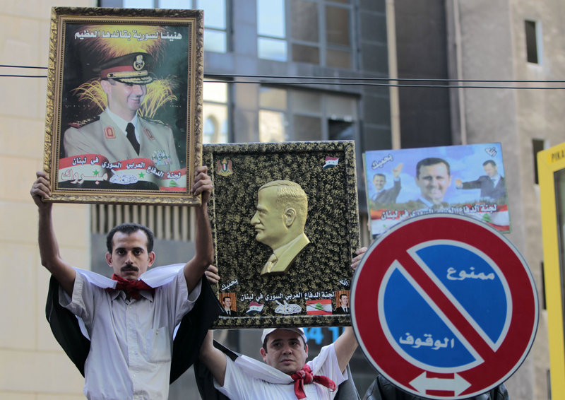 Pro-Syrian regime protesters in Beirut, Lebanon, hold up portraits of Syrian President Bashar Assad, left, and his father, Hafez Assad, right, during a demonstration against the Arab League decision to suspend Syria earlier this week.