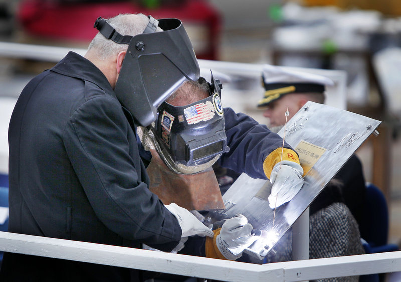Welder Carl Pepin is assisted by retired Marine Corps Lt. Col. James G. Zumwalt, left, as Pepin inscribes a steel plate at the keel-laying ceremony. The Zumwalt is named after Adm. Elmo “Bud” Zumwalt, a Navy legend whose career culminated in the early 1970s as chief of naval operations. The ship will be christened at another ceremony in 2013.