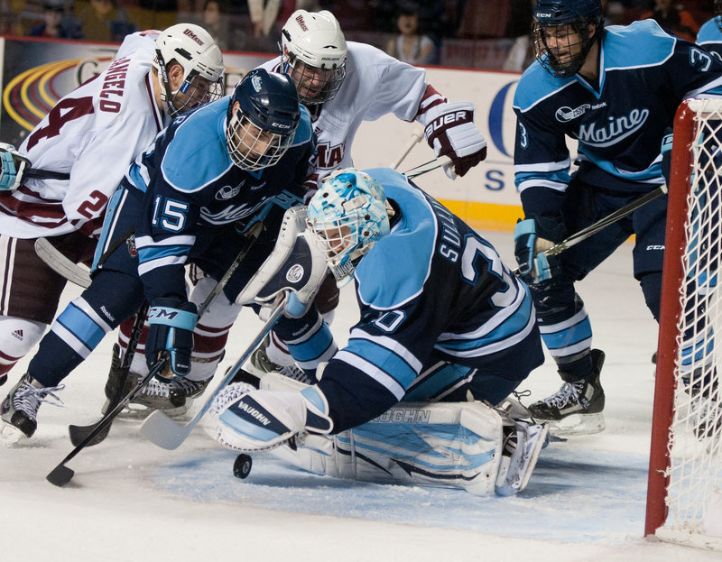 Maine goalie Dan Sullivan stays with the puck Friday night with help from defenders John Parker, left, and Mark Nemec as Massachusetts unleashes its offense during a 2-2 tie in a Hockey East game at Amherst, Mass.