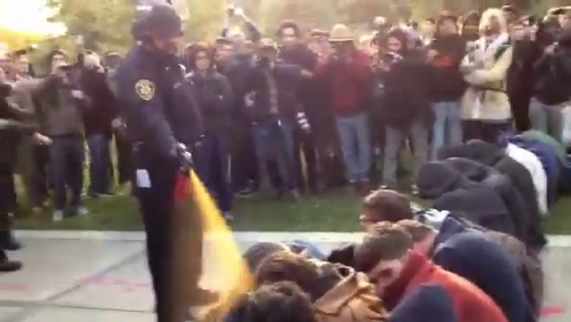 In this image made from video, an officer uses pepper spray as he walks down a line of Occupy demonstrators sitting on the ground at the University of California, Davis on Friday.