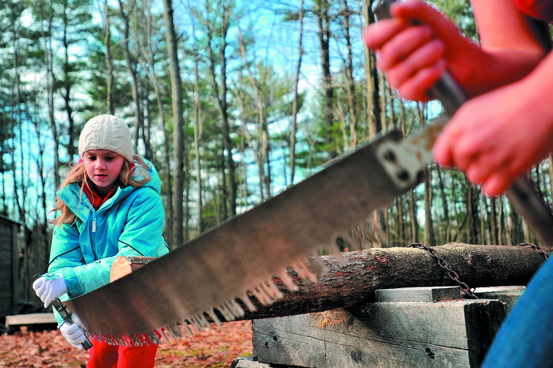 Emma Parrish, 9, of Oakland learns to use a crosscut saw with the help of Colby sophomore Liz Schell as part of the Adventure Girls program on Saturday at the college in Waterville.