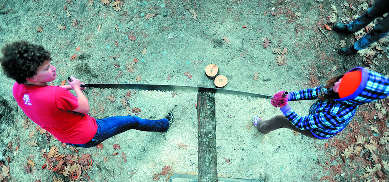 Liz Schell, left, introduces Morgaine Kmen, 10, to the crosscut saw on Saturday. Members of Colby College s Woodsmen s Team taught forestry skills to 14 girls in the Adventure Girls program, which introduces girls to male-dominated activities and jobs.