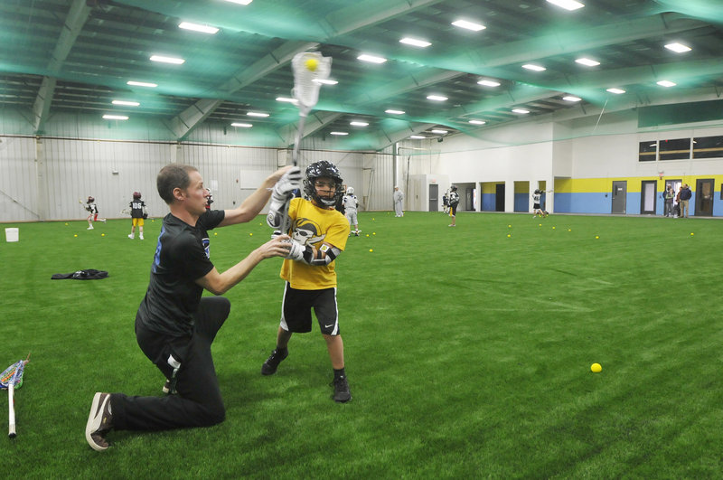 Deke Andrew works with Sean Dilworth, 9, of Falmouth during a lacrosse practice at the newly opened Riverside Athletic Center in Portland. The facility will cater to athletes passionate enough about one sport to want to play it year-round.