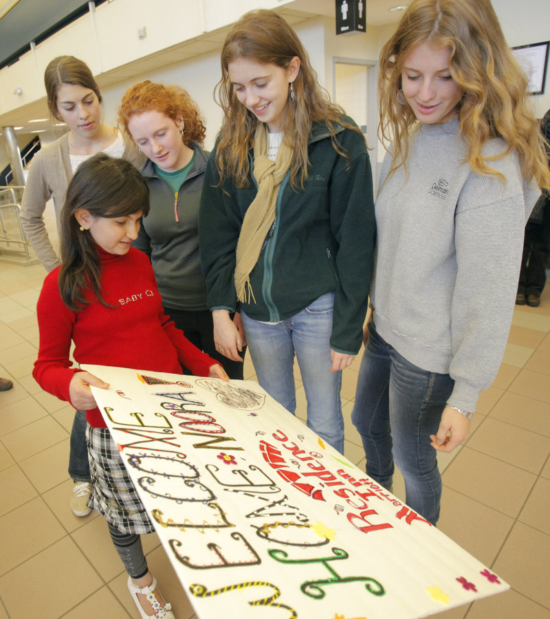 Noora Afif Abdulhameed shows a sign to Falmouth High students, from left, Marian Bergkamp, Clara Brown, Caroline Levy and Nevada Horne after her arrival Monday. The students will be doing art projects with Noora at the Ronald McDonald House.