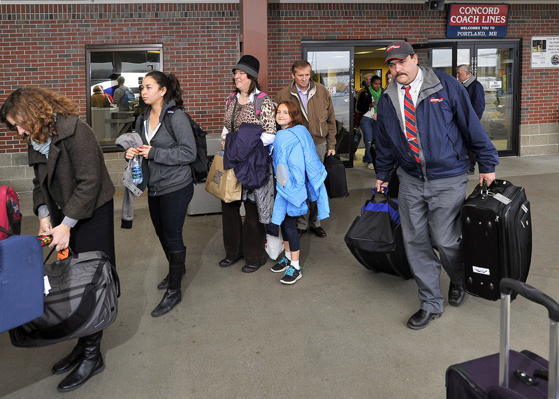 Chuck Eldridge, a motor coach operator for Concord, helps passengers with their baggage as they board the bus for Boston.