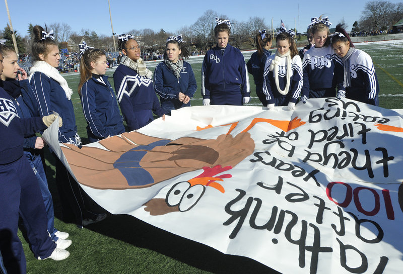 Portland High School cheerleaders prepare a banner before their team takes on Deering in the Thanksgiving Day football game.