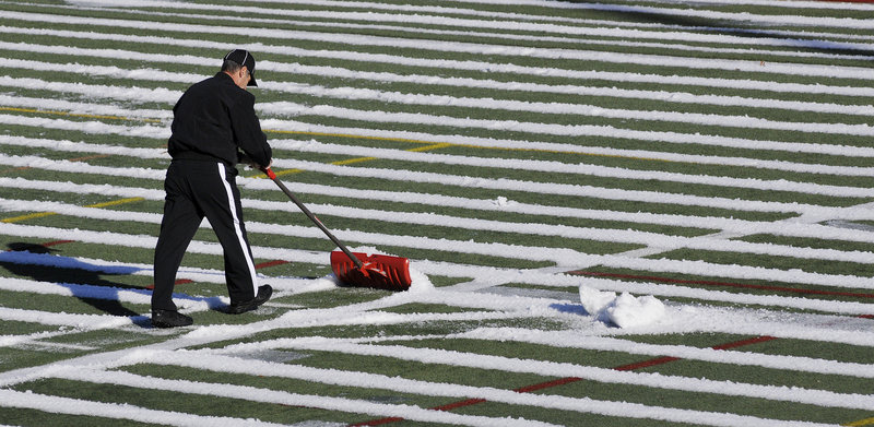 Kevin Martin shovels snow from the field before the start of Thursday's game. Deering beat Portland, but many football fans say the score isn't what matters.