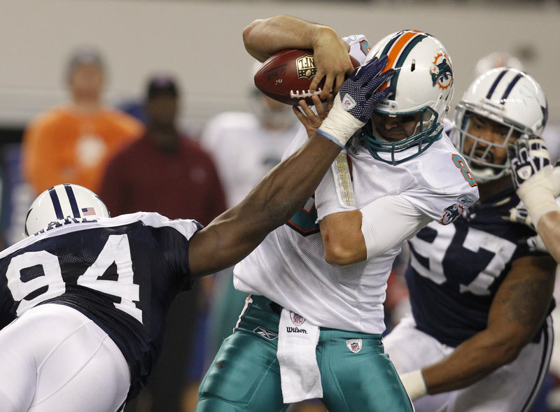 Miami quarterback Matt Moore attempts to hold the ball Thursday while being sacked by DeMarcus Ware of the Dallas Cowboys during the Cowboys’ 20-19 victory.
