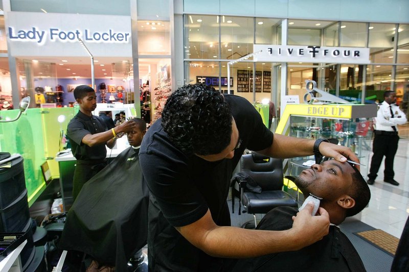 Percy Souder, owner of Edge Up barber shop inside the Westfield Culver City shopping center in Culver City, Calif., gives a haircut and shave to customer Jovan Bland, right, of Los Angeles. Haircuts, manicures, massages and more can be obtained now at shopping malls that formerly were strictly retail-focused.