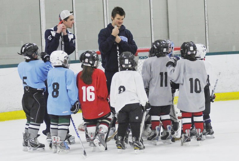 University of Maine goaltenders Martin Ouellette, left, and Dan Sullivan talk with young players Friday during a clinic at Family Ice Center in Falmouth. The Black Bears will play Clarkson tonight at the Cumberland County Civic Center.