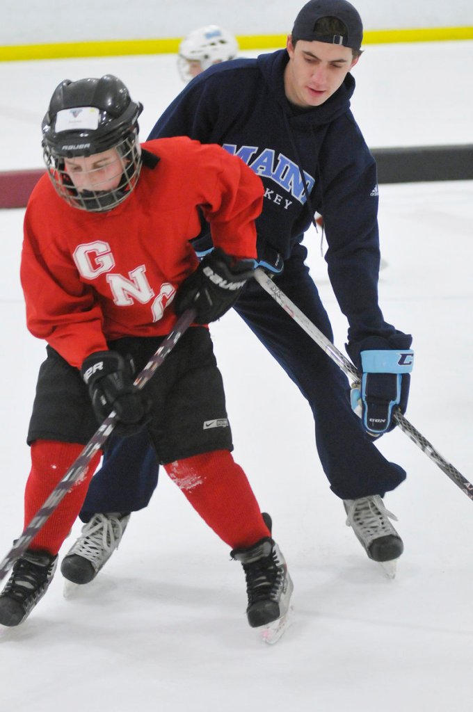 Andrew Topham, 10, of Gray tries to keep the puck from Connor Leen of UMaine during a drill as part of the clinic for Casco Bay Youth Hockey players.