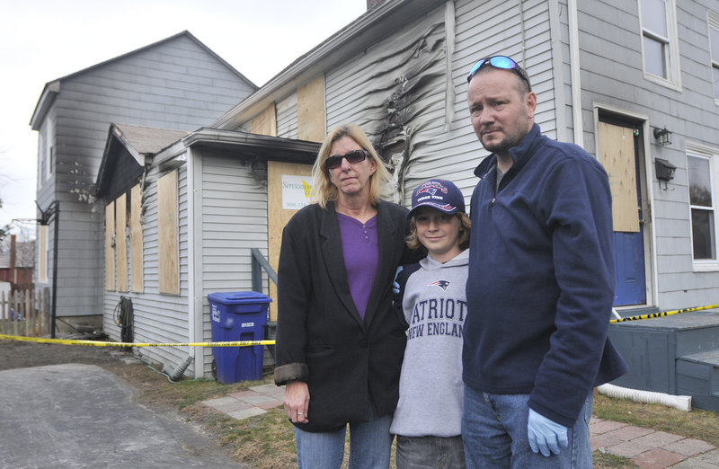 The Calkins family – Denise, 10-year-old Max and Mark – stand outside their fire-damaged home. Not pictured is son Sam Lennon, 16.