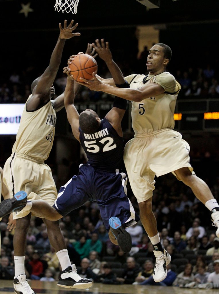 Tu Holloway of Xavier is fouled by Vanderbilt’s Lance Goulbourne, right, as Steve Tchiengang also defends during Monday’s game in Nashville, Tenn. Holloway made a pair of 3-pointers in overtime to propel Xavier to an 82-70 win.