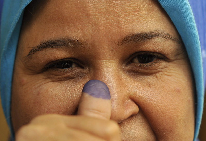 An Egyptian woman shows her inked finger after voting on Monday. Female voters appeared to outnumber men.