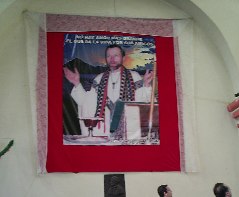 A photograph of the Rev. Stanley Rother is displayed inside the church he served in remote Santiago Atitlan, Guatemala. Atop the photo are the words, “There is no greater love than to give your life for your friends.”