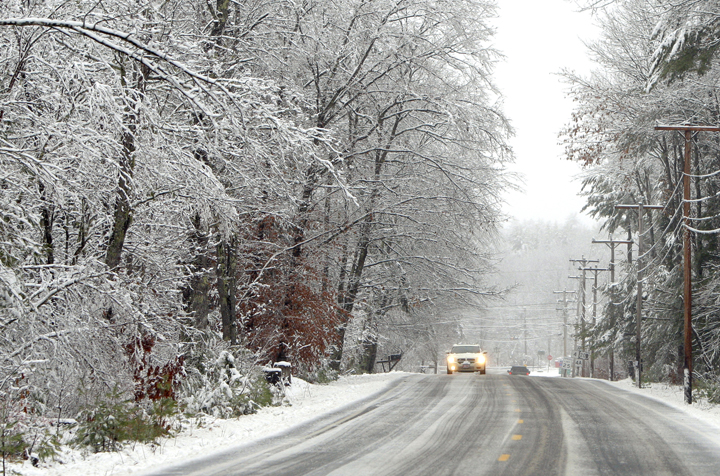 A car makes its way through the snow along Route 117 in Hollis today.