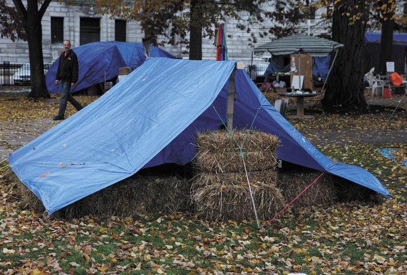 A pedestrian passes an Occupy Maine protester's tent insulated with hay bales on Tuesday on Nov. 15 in Portland.