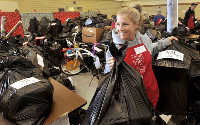 Salvation Army volunteer Cate Rust carries toy-filled bags out to waiting families Tuesday morning.