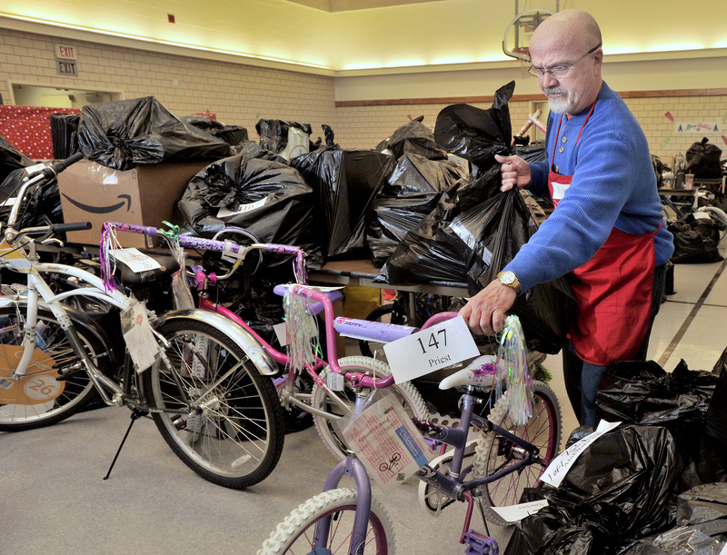 Volunteer Bob Parshley wheels out a bike along with another bag of toys to a waiting family Tuesday morning.