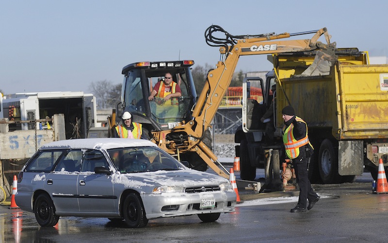 Shawn Patrick Ouellette / Staff Photographer Officer Brian McCarthy, right, redirects a driver trying to turn down Jetport Plaza Road from Western Avenue as workers try and repair a water main break Monday Dec. 26, 2011.